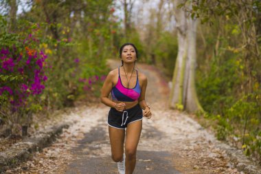 genç mutlu çekici ve egzotik Asya Endonezyalı koşucu kadın koşu egzersiz açık havada kırsal yol parça doğa arka plan neşeli çalışan 