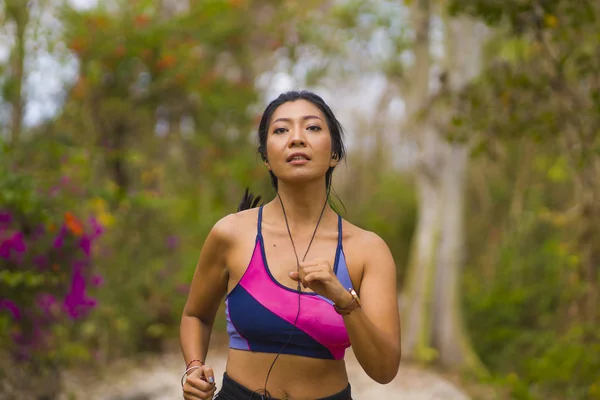 Giovane felice attraente ed esotico asiatico indonesiano corridore donna in jogging allenamento all'aperto in campagna strada pista natura sfondo in esecuzione allegro — Foto Stock