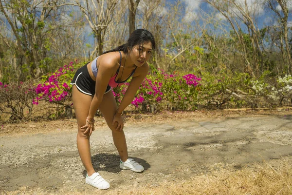 Young beautiful tired and breathless runner Asian woman exhausted and sweaty after hard running workout at trail road park in healthy lifestyle — Stock Photo, Image
