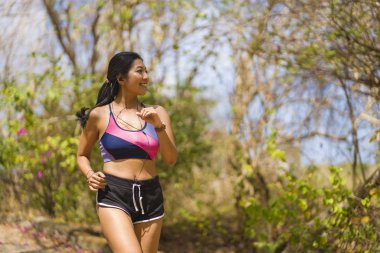 genç mutlu çekici ve egzotik Asya Endonezyalı koşucu kadın koşu egzersiz açık havada kırsal yol parça doğa arka plan neşeli çalışan 