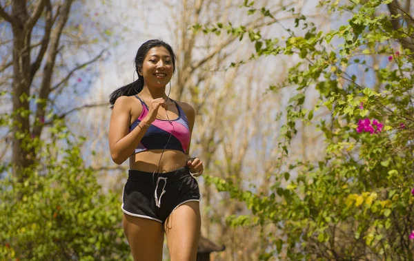 Giovane felice attraente ed esotico asiatico indonesiano corridore donna in jogging allenamento all'aperto in campagna strada pista natura sfondo in esecuzione allegro — Foto Stock