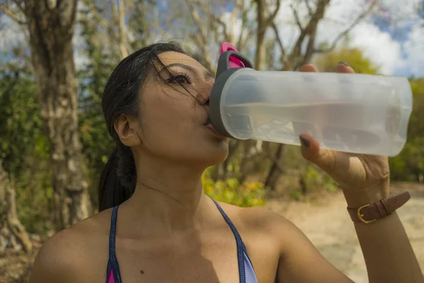 Utomhus livsstil porträtt av unga attraktiva trött och törstig asiatisk kvinna dricksvatten efter hårt rinnande träningspass kyla av på Beautiful Green Park — Stockfoto