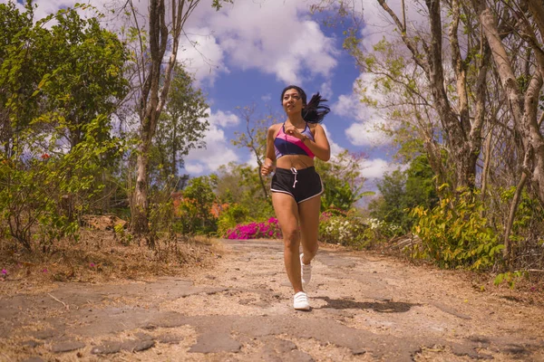 Joven atractivo y exótico asiático indonesio corredor mujer en trotar entrenamiento al aire libre en campo camino pista naturaleza corriendo sudoroso empujando duro —  Fotos de Stock