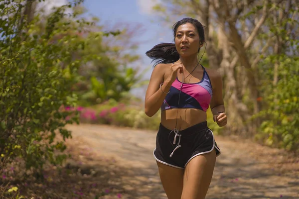 Young attractive and exotic Asian Indonesian runner woman in jogging workout outdoors at countryside road track nature running sweaty pushing hard — Stock Photo, Image