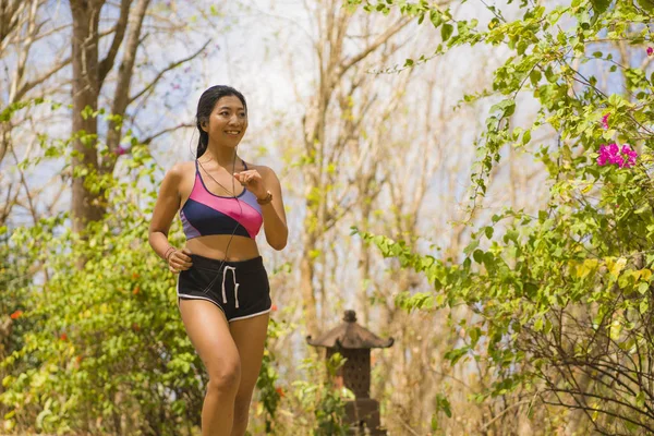 Giovane felice attraente ed esotico asiatico indonesiano corridore donna in jogging allenamento all'aperto in campagna strada pista natura sfondo in esecuzione allegro — Foto Stock