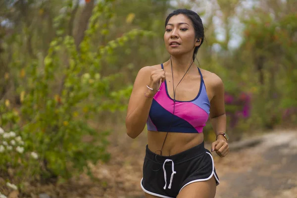 Young attractive and exotic Asian Indonesian runner woman in jogging workout outdoors at countryside road track nature running sweaty pushing hard — Stock Photo, Image