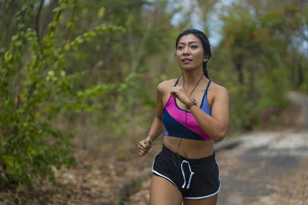 Joven atractivo y exótico asiático indonesio corredor mujer en trotar entrenamiento al aire libre en campo camino pista naturaleza corriendo sudoroso empujando duro — Foto de Stock