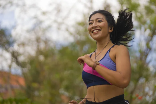 Joven feliz atractivo y exótico asiático indonesio corredor mujer en trotar entrenamiento al aire libre en campo camino pista naturaleza fondo corriendo alegre — Foto de Stock