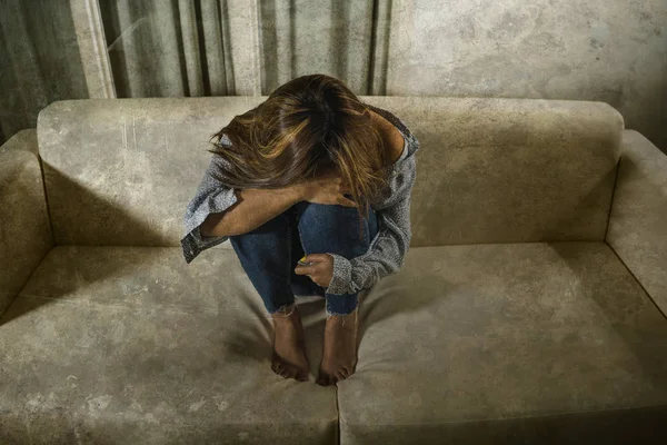 Retrato de una joven triste y deprimida llorando desesperada en el sofá de casa sintiendo el corazón roto sufriendo depresión crisis y problemas de ansiedad cubriendo su cara — Foto de Stock