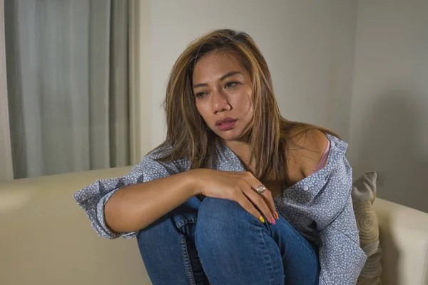 Young beautiful sad and depressed Asian woman in pain thoughtful and confused at home couch feeling broken heart suffering depression crisis and anxiety problem — Stock Photo, Image