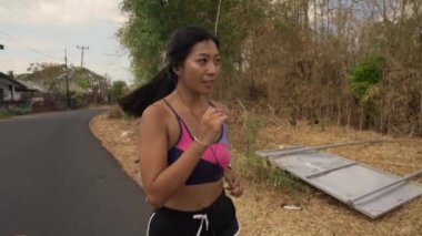 Yavaş hareket frontal geri gimbal genç egzotik uyum ve spor ve sağlıklı yaşam tarzı kavramı koşu egzersiz yapıyor asfalt yolda çalışan güzel Asya Endonezyalı kadın dolly tarzında vurdu çekin