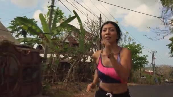 拉回Gimbal拍摄在多利风格的年轻异国情调的适合和美丽的亚洲印尼女人在沥青路上跑做慢跑锻炼的运动和健康的生活方式概念 — 图库视频影像