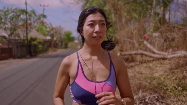 慢动作正面拉回云巴拍摄在多利风格的年轻异国情调的适合和美丽的亚洲印尼女人在沥青路上跑做慢跑锻炼的运动和健康的生活方式概念 — 图库视频影像