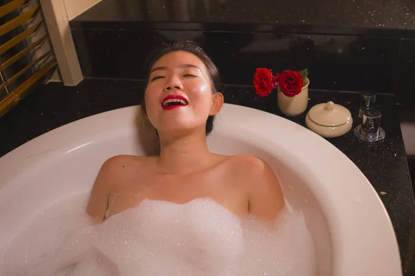 Ung vacker glad och glad asiatisk koreansk kvinna bada hemma eller lyxhotell badrum med ett skum bad i badkaret njuter leende avslappnad — Stockfoto