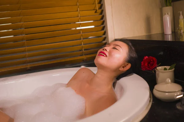 Joven hermosa feliz y alegre mujer asiática coreana bañarse en casa o baño de lujo hotel tener un baño de espuma en la bañera disfrutando sonriente relajado —  Fotos de Stock