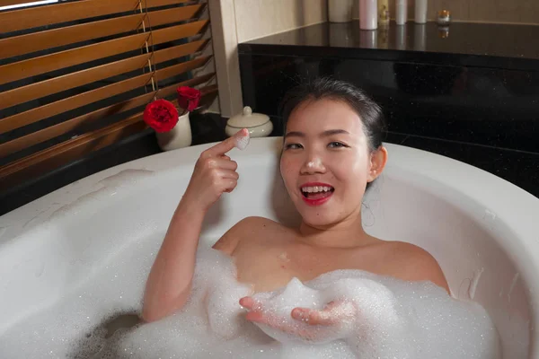 Jovem bonita feliz e alegre mulher chinesa asiática tomando banho em casa ou banheiro do hotel de luxo ter um banho de espuma na banheira desfrutando de sorrir relaxado — Fotografia de Stock