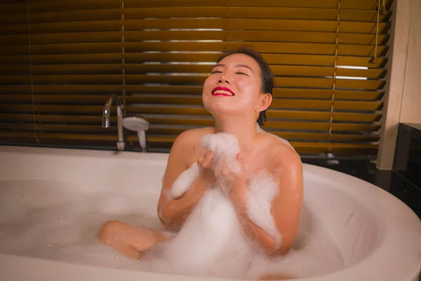 Joven hermosa feliz y alegre mujer china asiática bañándose en casa o baño de lujo hotel que tiene un baño de espuma en la bañera disfrutando sonriente relajado —  Fotos de Stock