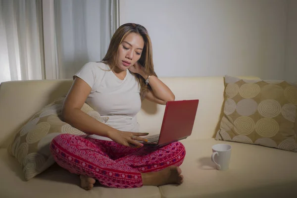 Jeune femme attrayante et naturelle en pantalon de pyjama détendue sur le canapé réseautage en utilisant ordinateur portable achats en ligne ou travailler et étudier — Photo