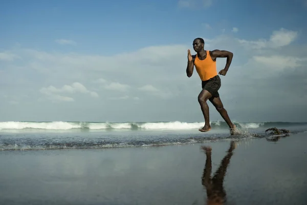 Retrato atlético de cuerpo completo de joven atractivo y en forma afroamericano negro corriendo en la playa haciendo ejercicio de fitness de verano corriendo en el mar en concepto de estilo de vida saludable — Foto de Stock