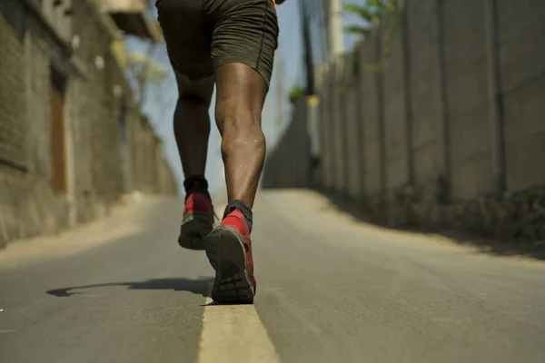 Rückenansicht im Detail des athletischen schwarzafrikanisch-amerikanischen Profisportlers Beine und Füße in Laufschuhen beim Training im Freien auf Asphaltstraße beim harten Jogging-Training — Stockfoto