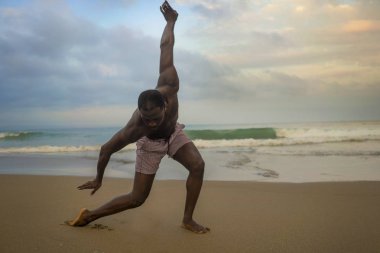 dramatik çağdaş dans koreograf bale plaj egzersiz yapıyor, genç çekici ve atletik afro siyah Amerikan adam gün doğumunda dans 