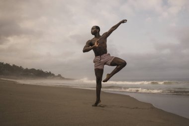 dramatik çağdaş dans koreograf bale plaj egzersiz yapıyor, genç çekici ve atletik afro siyah Amerikan adam gün doğumunda dans 