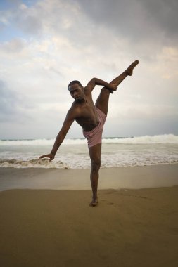 dramatik çağdaş dans koreograf bale plaj egzersiz yapıyor, genç çekici ve atletik afro siyah Amerikan adam gün doğumunda dans 