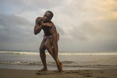 dramatik çağdaş dans koreograf bale plaj egzersiz yapıyor, genç çekici ve atletik afro siyah Amerikan adam gün doğumunda dans 