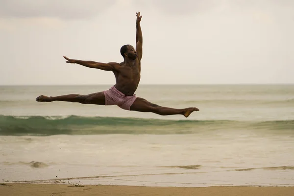 Coreógrafo de danza contemporánea haciendo ejercicios de ballet playa. joven atractivo y atlético negro afroamericano hombre bailando en la salida del sol saltando elegante — Foto de Stock