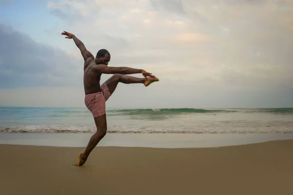 Dramático coreógrafo de danza contemporánea haciendo ejercicios de ballet playa, joven atractivo y atlético afro negro hombre americano bailando al amanecer — Foto de Stock