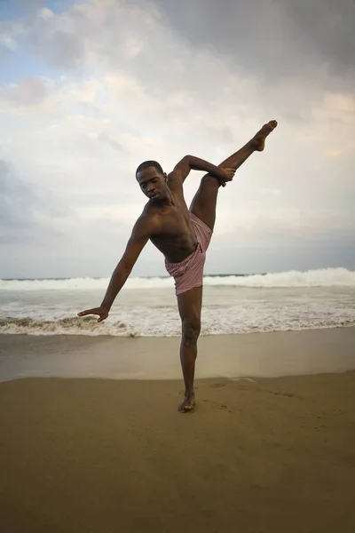 Dramático coreógrafo de danza contemporánea haciendo ejercicios de ballet playa, joven atractivo y atlético afro negro hombre americano bailando al amanecer — Foto de Stock