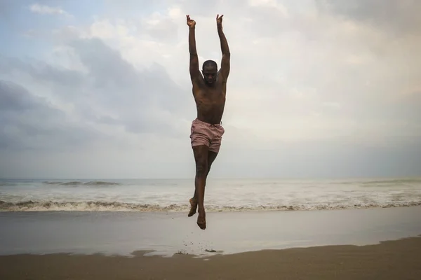 Dramatic contemporary dance choreographer doing ballet beach workout . young attractive and athletic afro black American man dancing on sunrise jumping — Stock Photo, Image