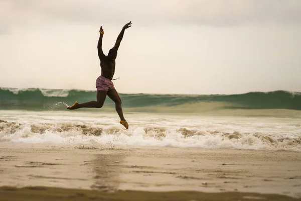 Dramatic contemporary dance choreographer doing ballet beach workout . young attractive and athletic afro black American man dancing on sunrise jumping — Stock Photo, Image