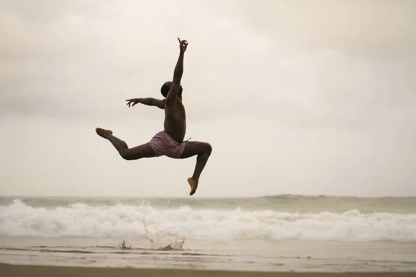 Dramático coreógrafo de danza contemporánea haciendo ejercicios de ballet playa. joven atractivo y atlético afro negro americano hombre bailando en la salida del sol saltar — Foto de Stock