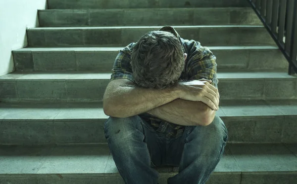Драматичний стиль життя портрет молодого пригніченого і сумного чоловіка, що сидить на відкритому повітрі на темних вуличних сходах, що страждають проблемою депресії і тривожною кризою, що плаче відчайдушно — стокове фото