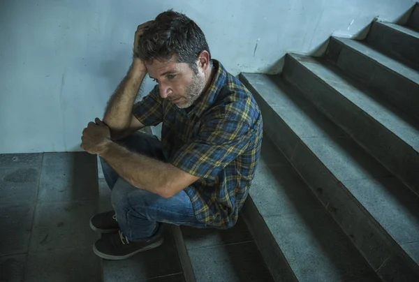 Dramatic lifestyle portrait of young depressed and sad man sitting outdoors on dark street staircase suffering depression problem and anxiety crisis crying desperate — Stock Photo, Image