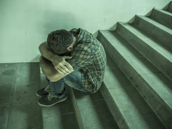 Drammatico ritratto stile di vita di un giovane uomo depresso e triste seduto all'aperto su una scala scura che soffre di depressione problema e ansia crisi disperata — Foto Stock