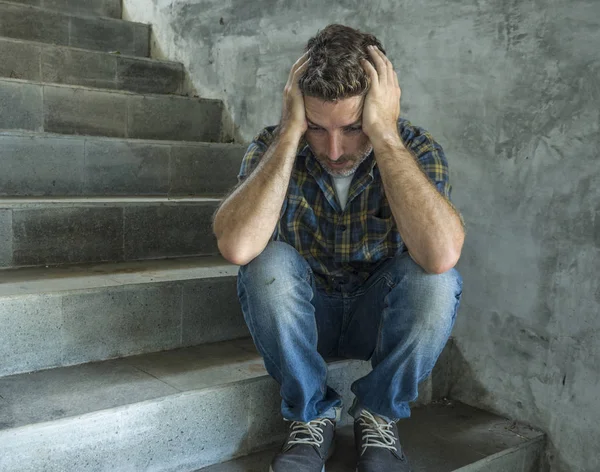 Молодий депресивний і сумний чоловік, сидячи на вулиці на темних вуличних сходах, страждає проблемою депресії, виглядає стурбованим мисленням і почуттям нещасного — стокове фото