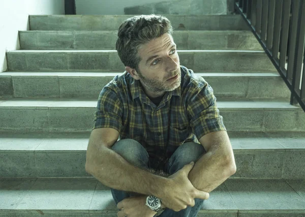 genç depresif ve üzgün adam karanlık sokak merdiveni üzerinde tek başına oturan depresyon sorunu endişeli düşünme ve sefil duygu bakıyor acı