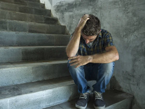 Dramatisches Lebensstil-Porträt eines jungen depressiven und traurigen Mannes, der draußen auf einer dunklen Straßentreppe sitzt und unter Depressionen und Angstzuständen leidet und verzweifelt weint — Stockfoto