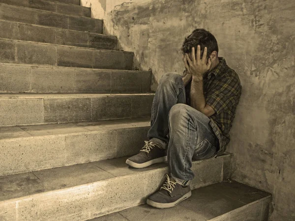 Dramatic lifestyle portrait of young depressed and sad man sitting outdoors on dark street staircase suffering depression problem and anxiety crisis crying desperate — Stock Photo, Image