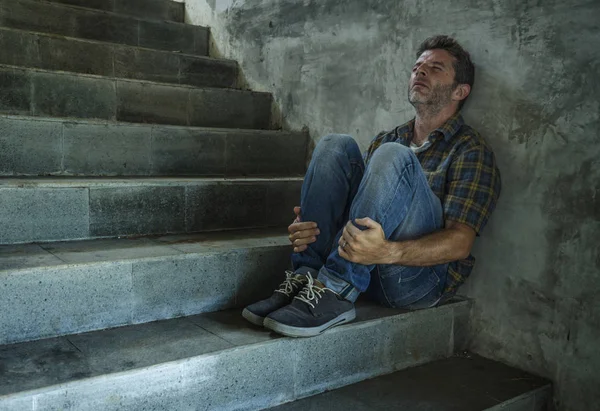 Dramatisches Lebensstil-Porträt eines jungen depressiven und traurigen Mannes, der draußen auf einer dunklen Straßentreppe sitzt und unter Depressionen und Angstzuständen leidet und verzweifelt weint — Stockfoto