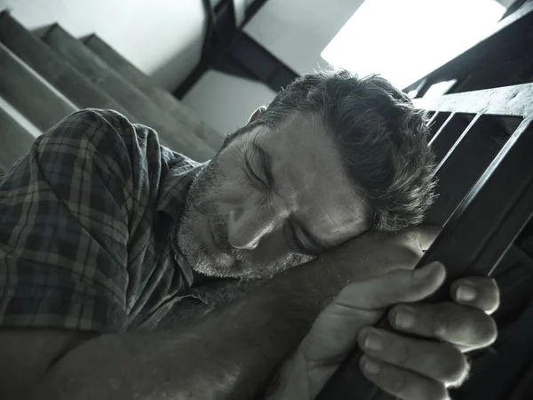 Dramatisches Porträt eines jungen depressiven und paranoiden Mannes, der im Freien auf der Treppe einer dunklen Grunge-Straße an der Ecke sitzt und sich krank fühlt und Depressionen und Angstzustände erleidet — Stockfoto