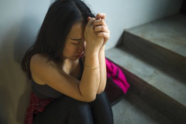 Asyalı kız üniversite öğrencisinin dramatik portresi zorbalık. Genç depresif ve üzgün Koreli kız kampüs merdivenlerinde yalnız oturan zorbalık ve taciz acı