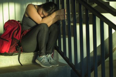 ve üzgün Koreli kız kampüs merdivenlerinde yalnız oturan zorbalık ve Asyalı kız üniversite öğrencisi nin taciz dramatik portre zorbalık acı. Genç depresif ve üzgün Koreli kız yalnız oturan