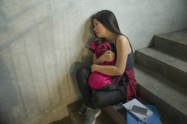 Asyalı kız üniversite öğrencisinin dramatik portresi zorbalık. Genç depresif ve üzgün Çinli kız kampüs merdivenlerinde yalnız oturan zorbalık ve taciz acı