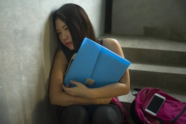 Retrato dramático de uma estudante universitária asiática intimidada. Jovem deprimida e triste menina coreana sentada sozinha na escadaria do campus sofrendo bullying e assédio — Fotografia de Stock