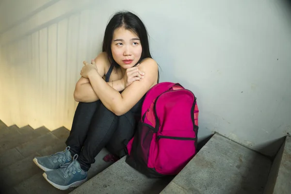 Drámai portréja ázsiai női főiskolai hallgató terrorizálják. Fiatal depressziós és szomorú kínai lány ül magányos a campus lépcsőházban szenvedés megfélemlítés és zaklatás — Stock Fotó