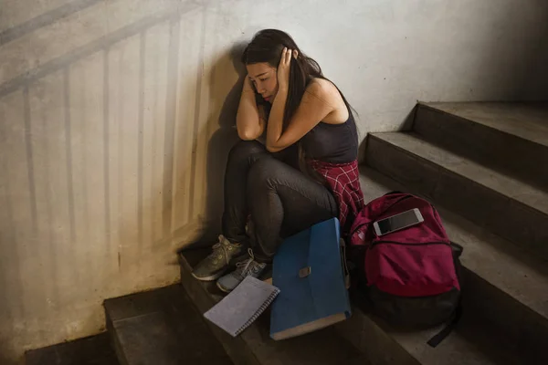 Retrato dramático de uma estudante universitária asiática intimidada. Jovem deprimida e triste menina japonesa sentada sozinha na escadaria do campus sofrendo bullying e assédio — Fotografia de Stock