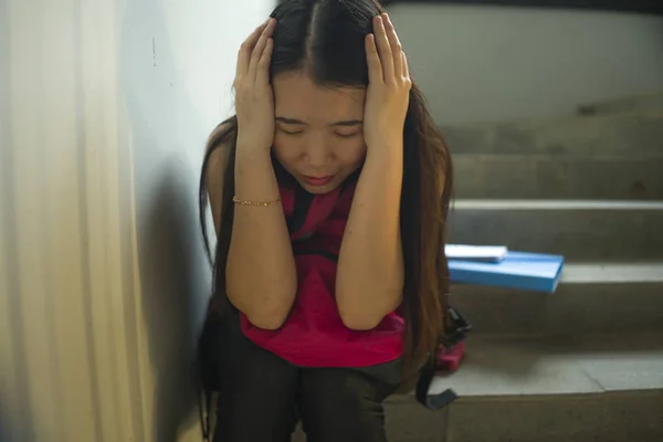 Joven hermosa deprimida asiática japonesa estudiante universitaria sentada en la escalera víctima de abuso sintiéndose asustada y sola siendo acosada y acosada —  Fotos de Stock